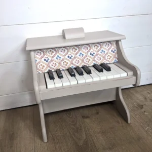 Détail du tissu à fleurs sur le piano en bois beige vieilli