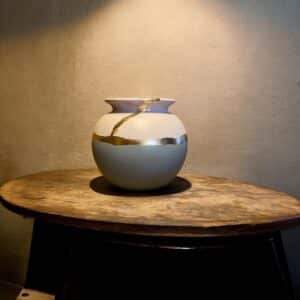 Vase rond blanc et bleu ciel posé sur une table en bois rustique