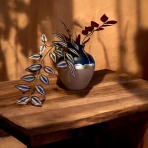 Vase rond rose poudré et bleu marine posé sur une table en bois rustique, avec un bouquet