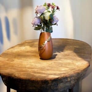 Vase Terracotta avec deux moulures oiseaux recouverts de feuille d’or posé sur une table en bois rustiqueAvec un bouquet champêtre