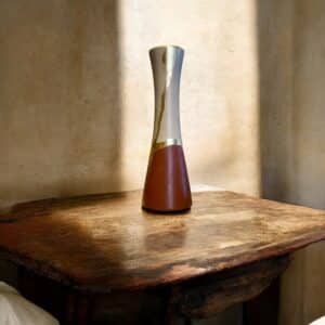 Grand vase beige et bordeaux avec un liseré en feuille d’or posé sur une table en bois rustique