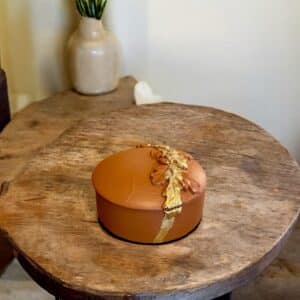 Boîte à bijoux terracotta avec des moulures en fleurs et de la feuille d’or posée sur une table en bois rustique