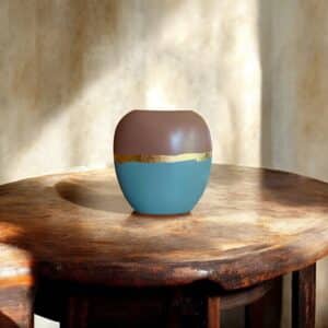 Vase marron glacé et gris bleu posé sur une table en bois rustique