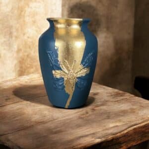 Vase bleu marine avec une moulure papillon et de le feuille d'or posé sur une table en bois rustique