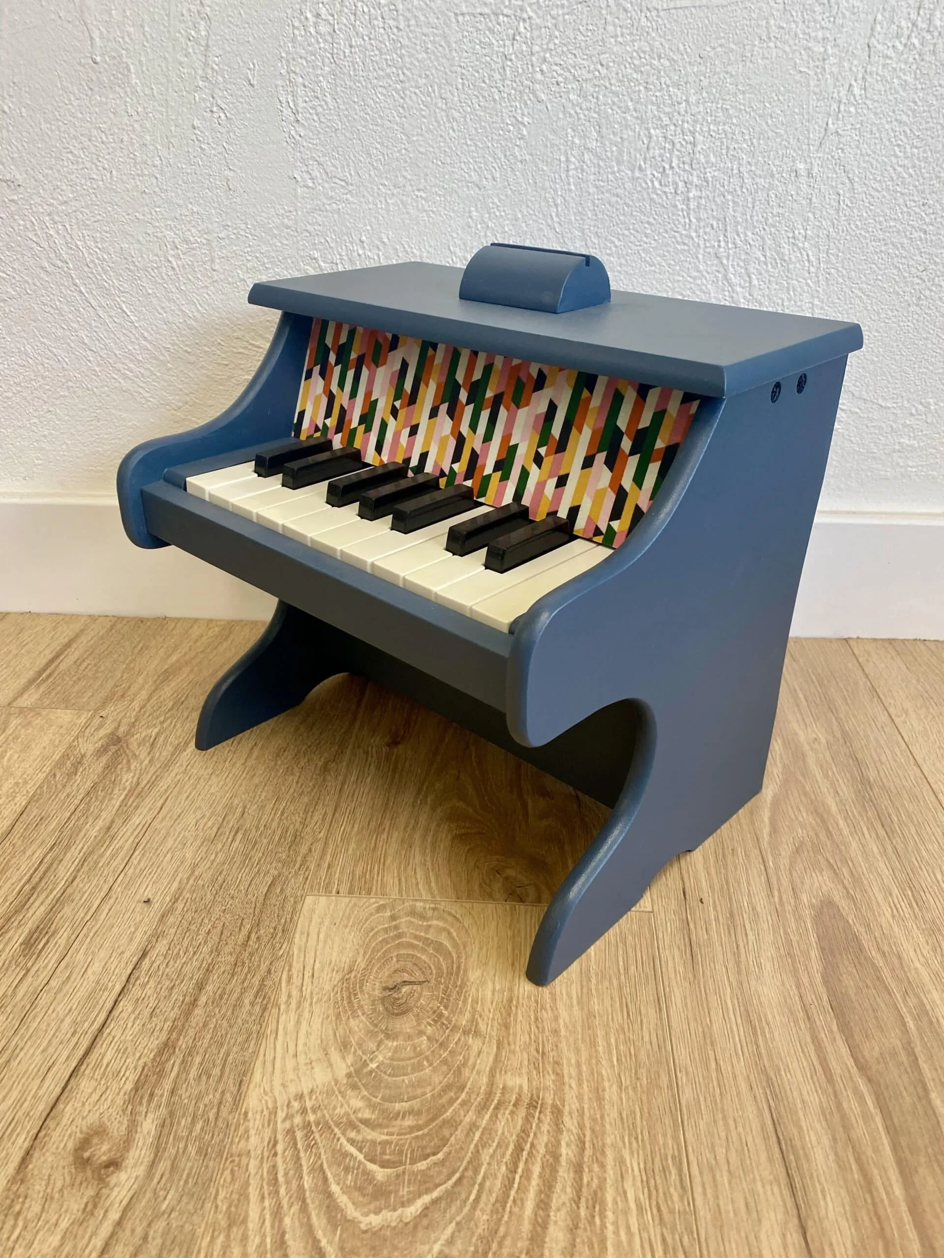 Piano en bois bleu nuit relooké à la main, détail du tissu coloré